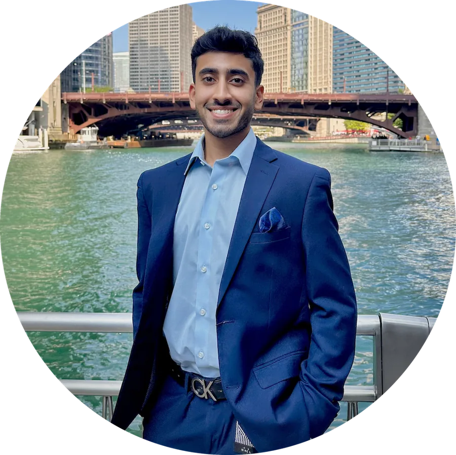 Portrait of Chiraag Nadig in a navy suit beside the Chicago River